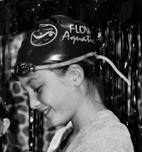 -black-and-white-photo-of-a-swimmer-standing-on-an-awards-stand-at-flow-aquatics-swim-school